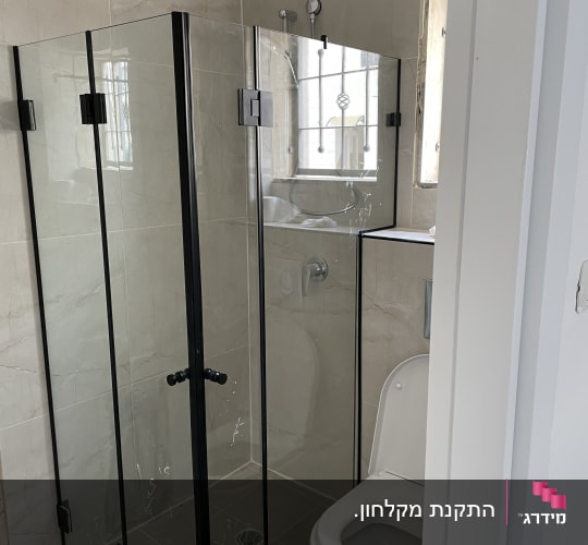 מקלחון זכוכית עם דלתות שחורות בחדר אמבטיה